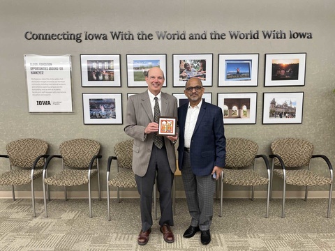 Russell Ganim with Anant Chakradeo in front of International Programs photos and "connecting Iowa with the world and the world with Iowa"