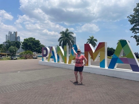 Julia Kleinschmit standing in front of rainbow Panama sign
