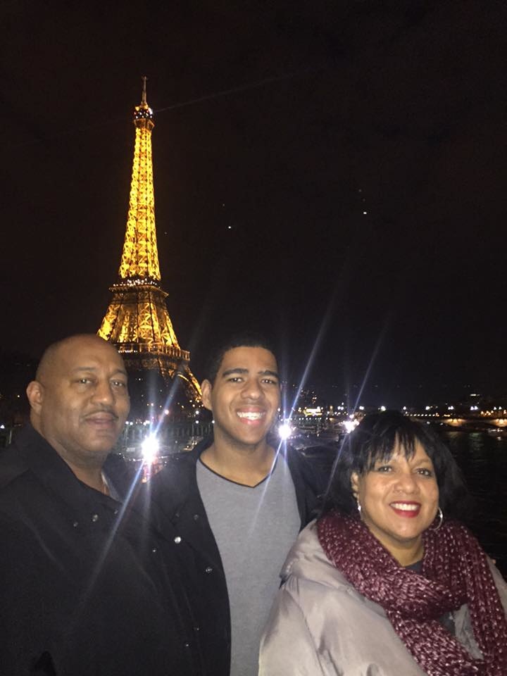 Marcus poses in front of the Eiffel Tower with his parents