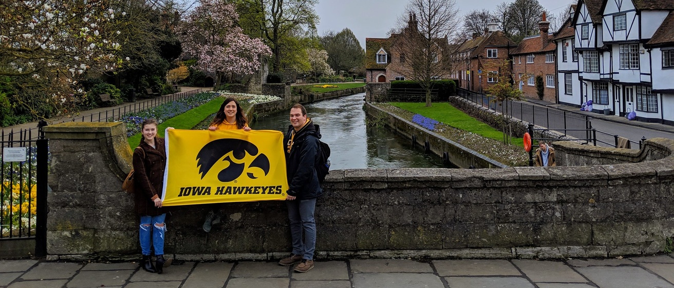 students holding hawkeye flag on bridge in Europe