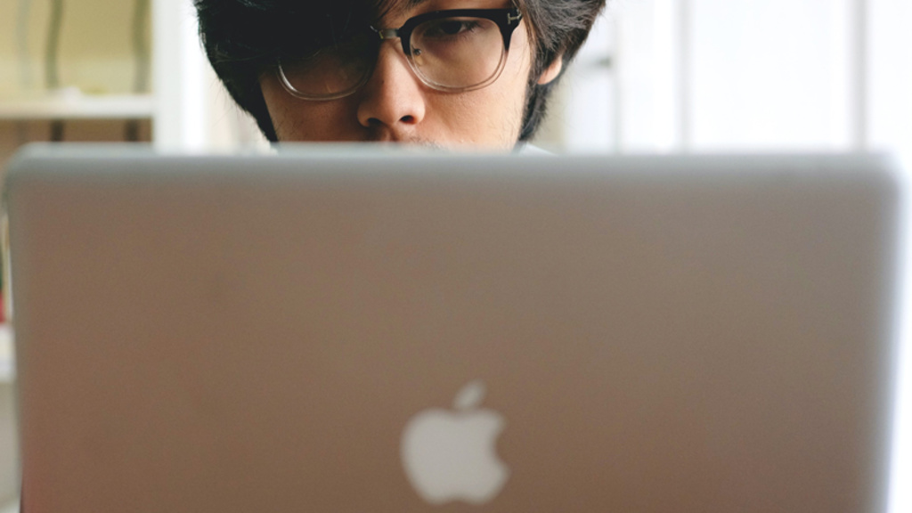 male wearing glasses looking at laptop