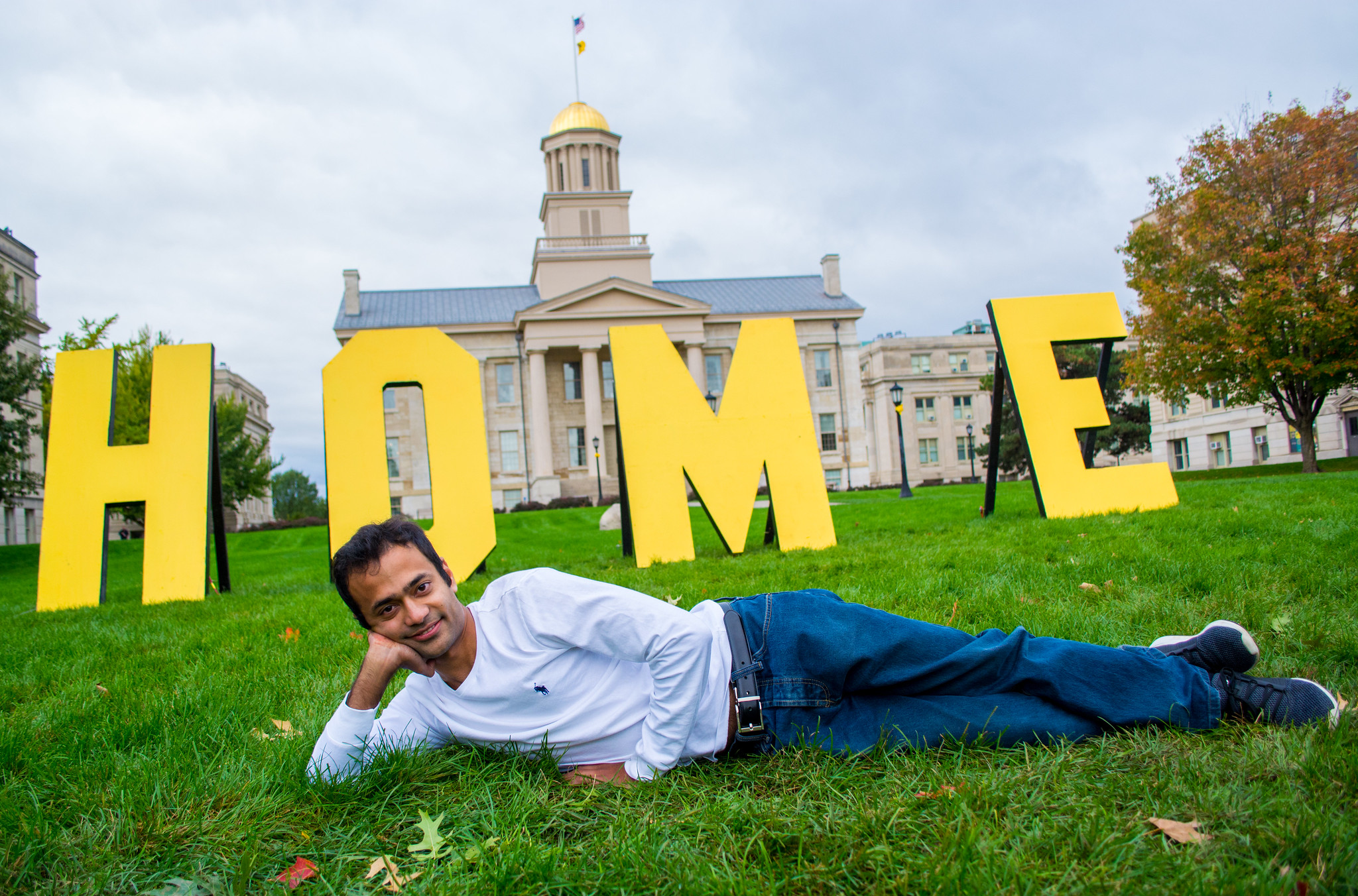 student lying on pentacrest in front of Home sign