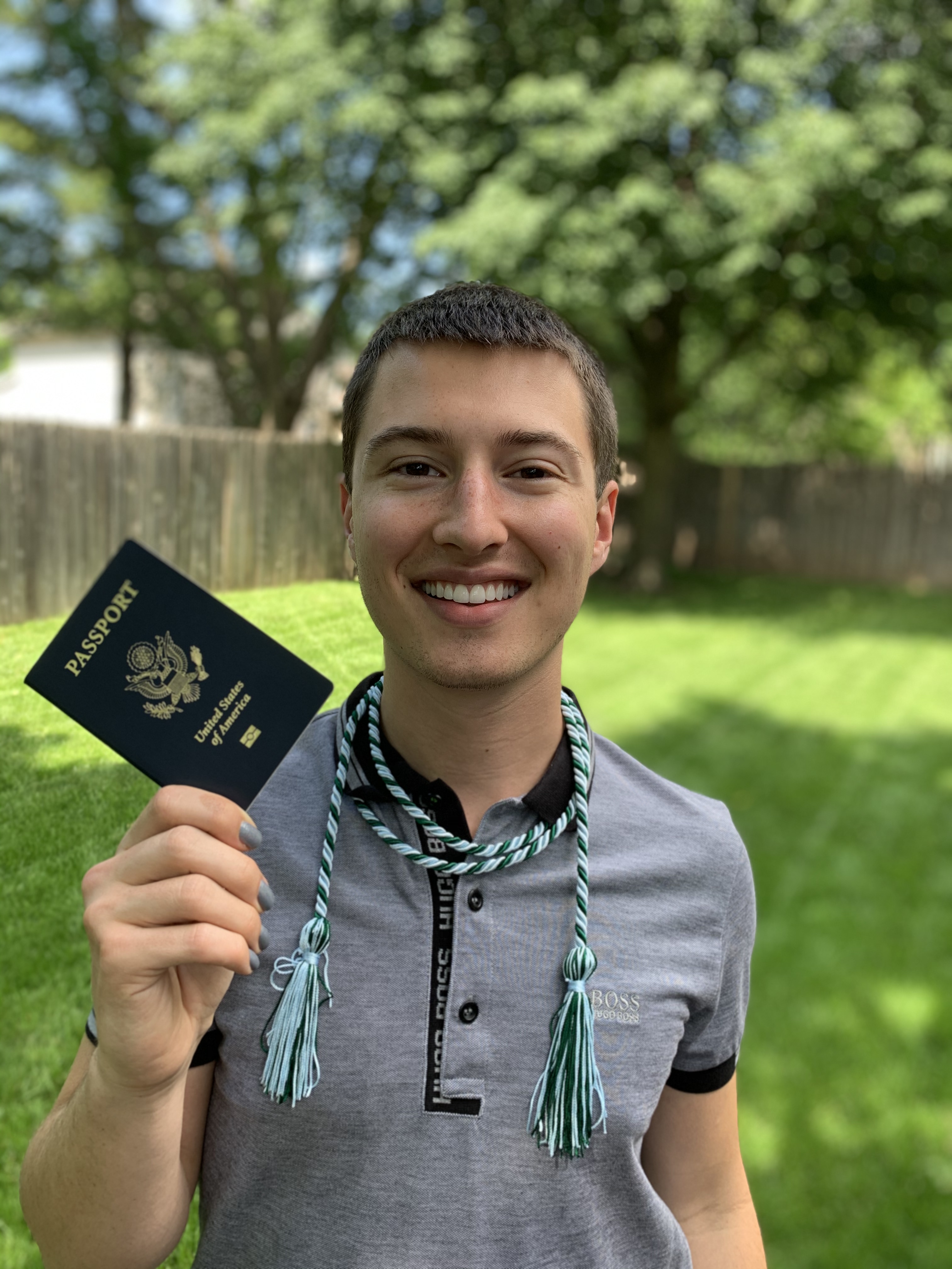 Student holding passport wearing study abroad graduation cord