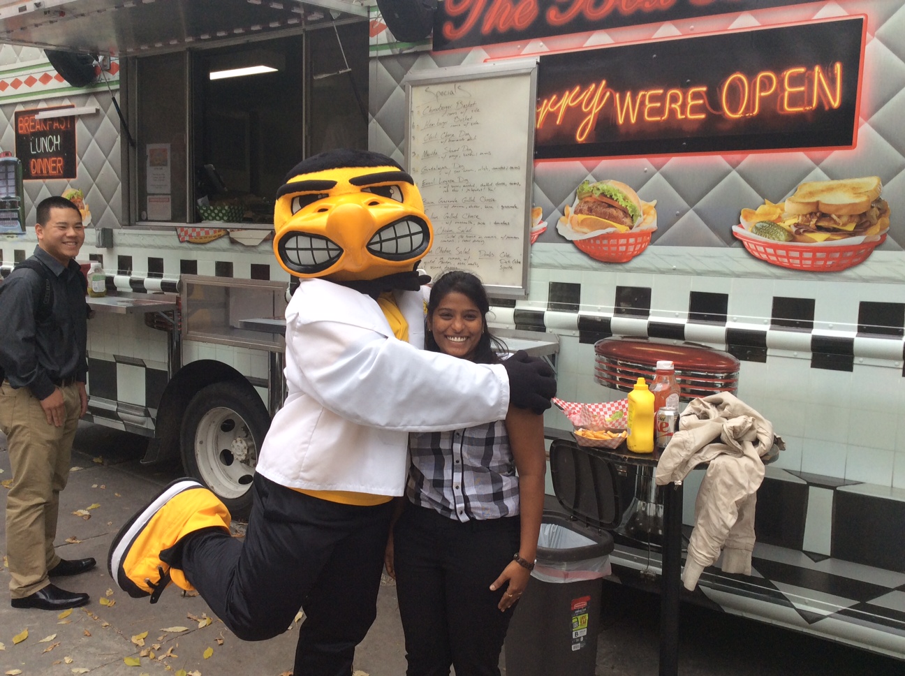 student in front of food truck being hugged by Herky