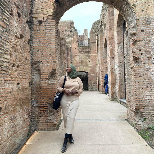 Sauda Abdullahi walking through stone buildings in Europe