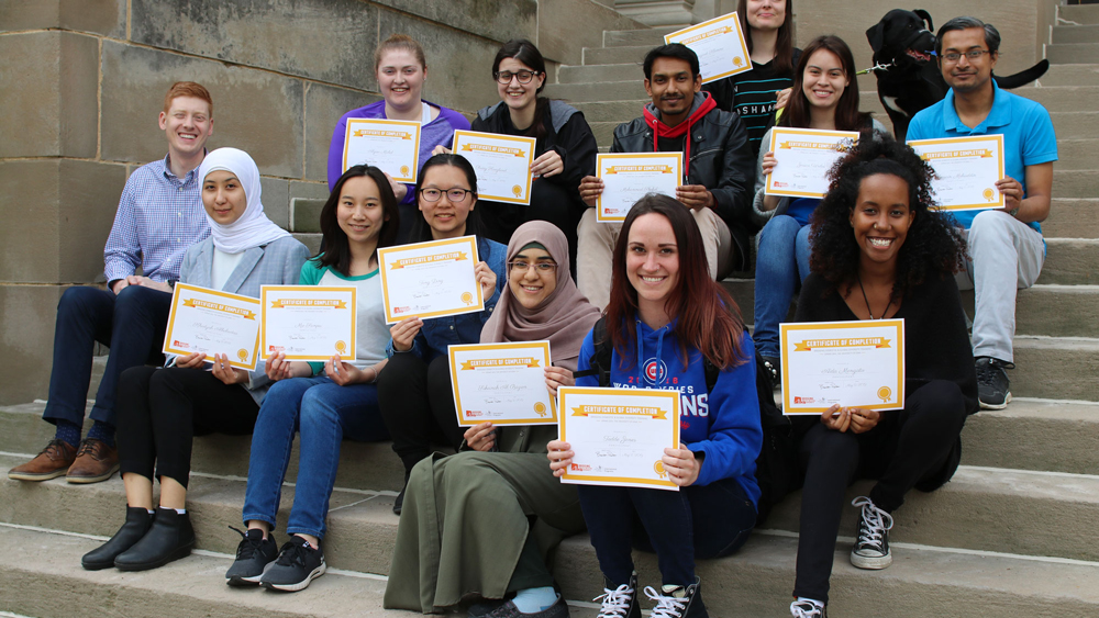 students sitting on steps holding certificates