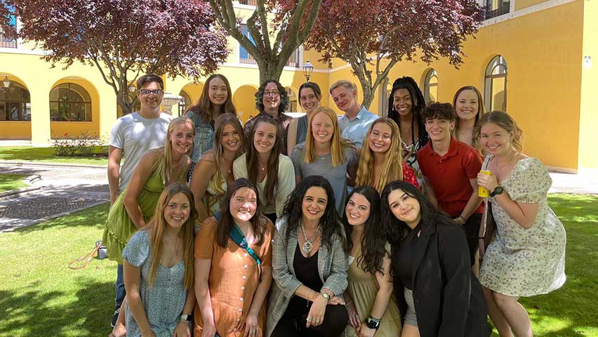 students and faculty member under flowering tree in park in Spain