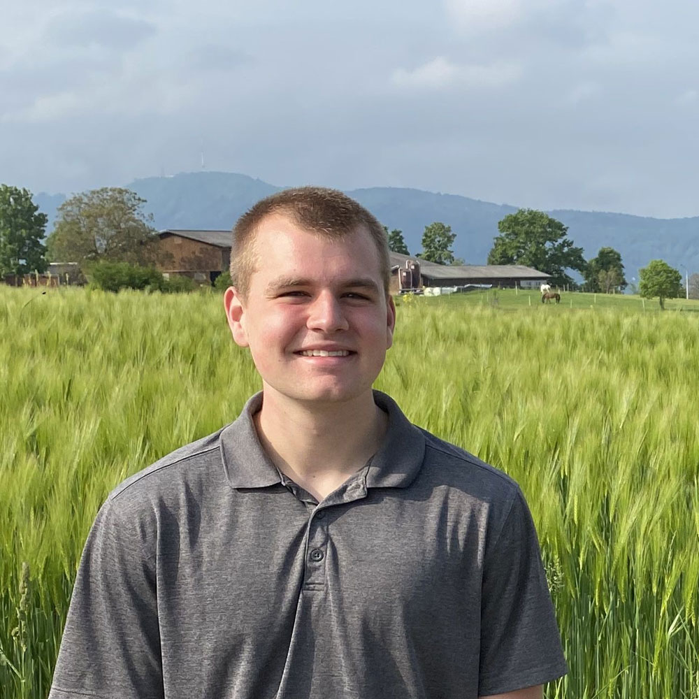 Cade Hoambrecker in green field and mountains