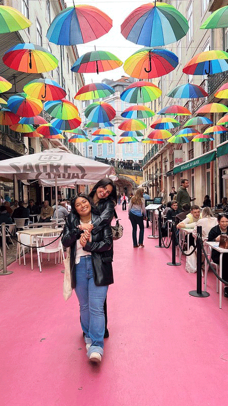 Reet Oberoi in Lisbon Portugal under colorful umbrellas on pink street