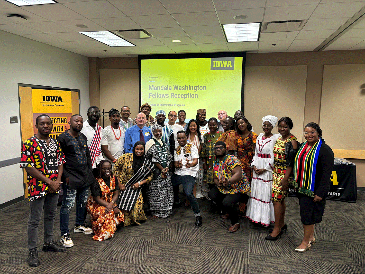 Mandela Fellows dressed in traditional African dress with Russ Ganim in front of slide that says Mandela Washington Fellows Reception