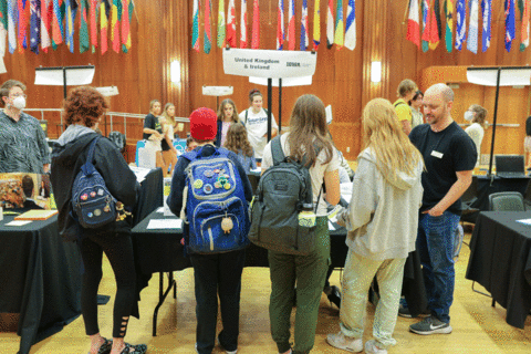 students standing with back to camera, facing UK and Ireland table at study abroad fair