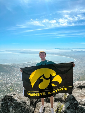Alex Hefel with scenic background holding Hawkeye flag