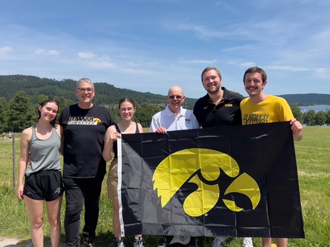 Russ Ganim with others holding Iowa flag in mountains in Germany