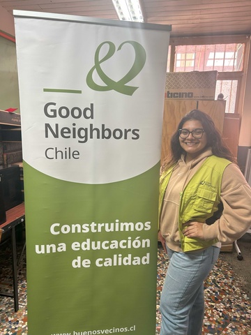 Guadalupe de la Rosa standing in front of banner with Good Neighbors Chile