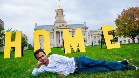 student laying in front of letters HOME in front of Univ. of Iowa old capitol building