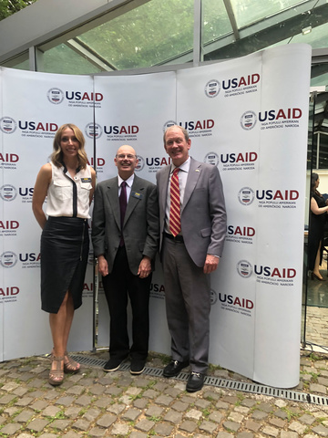 Cassie Barnhardt, Russ Ganim, and Curt Youngs in front of USAID sign