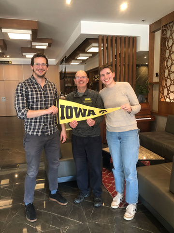 Russ Ganim with Ardi Mejzini and Charlotte Hilker with Iowa banner