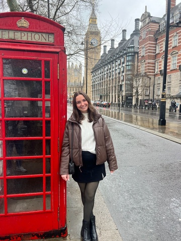 Kate Burns standing next to a London phone booth