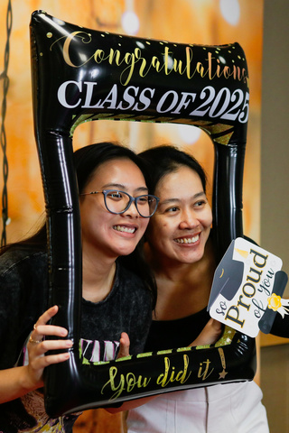 Two students holding a frame around their faces that says "congratulations class of 2025" while standing in a Photo Booth.