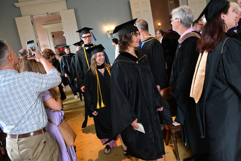 students in cap and gown smiling as they walk to seats