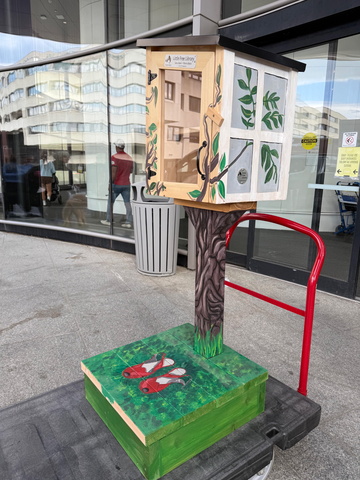 Little Free Library with a green stand being wheeled into hospital on a cart outside