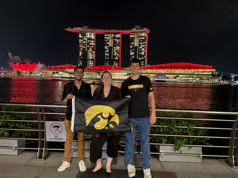 Monica Ernberger holding a Hawkeye flag with UI students in Singapore