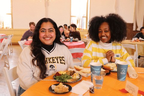 Students sitting at table with plates of Thanksgiving food