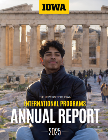 student sitting in front of Greek ruins smiling; International Programs Annual Report 2025, Iowa