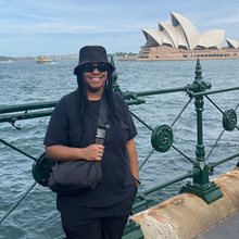 student poses for photo in front of Sydney Opera House
