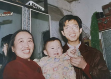 A man and woman lovingly hold a baby in a cozy room, surrounded by soft lighting and warm decor.