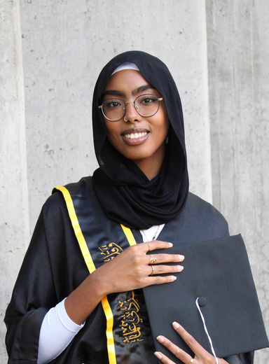 student wearing hijab and holding graduation cap 