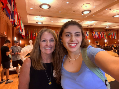 student in blue shirt posing with women in black dress