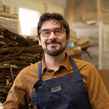 man wearing an apron and glasses smiling