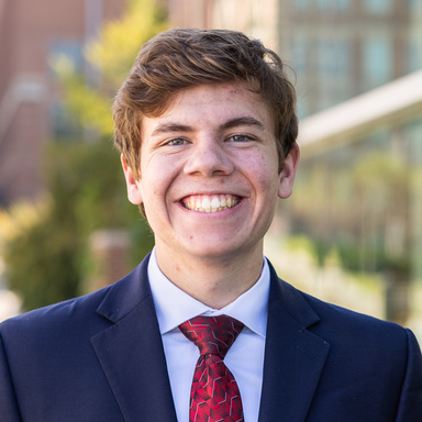 student in suit and tie smiling