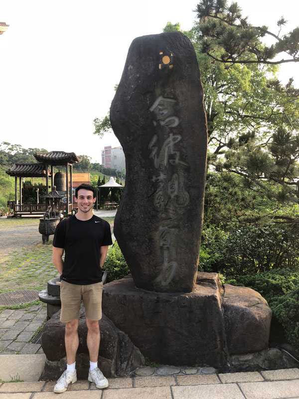Brett Burk standing near stone with Chinese characters