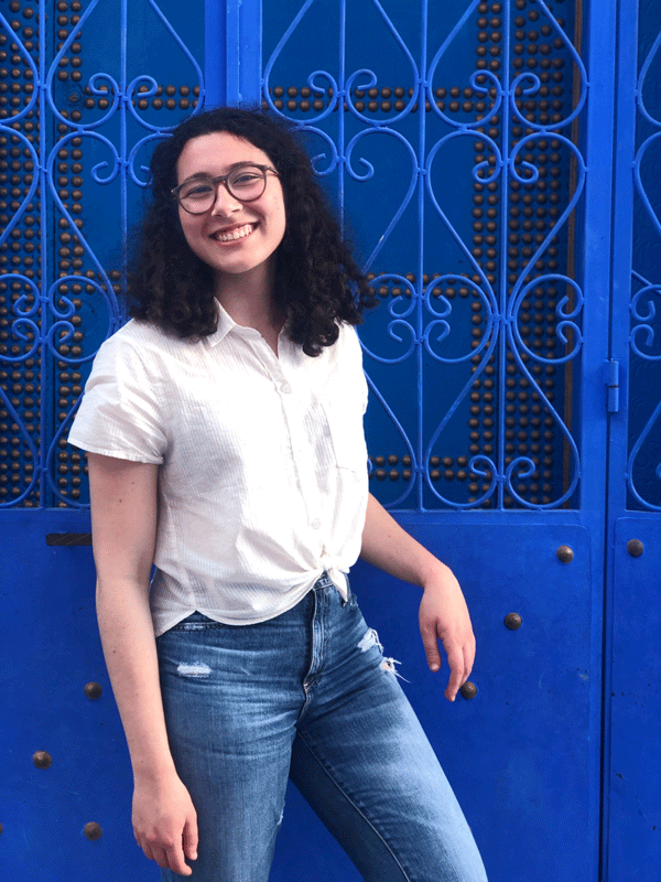 A smiling Isabella Senno in front of blue gate