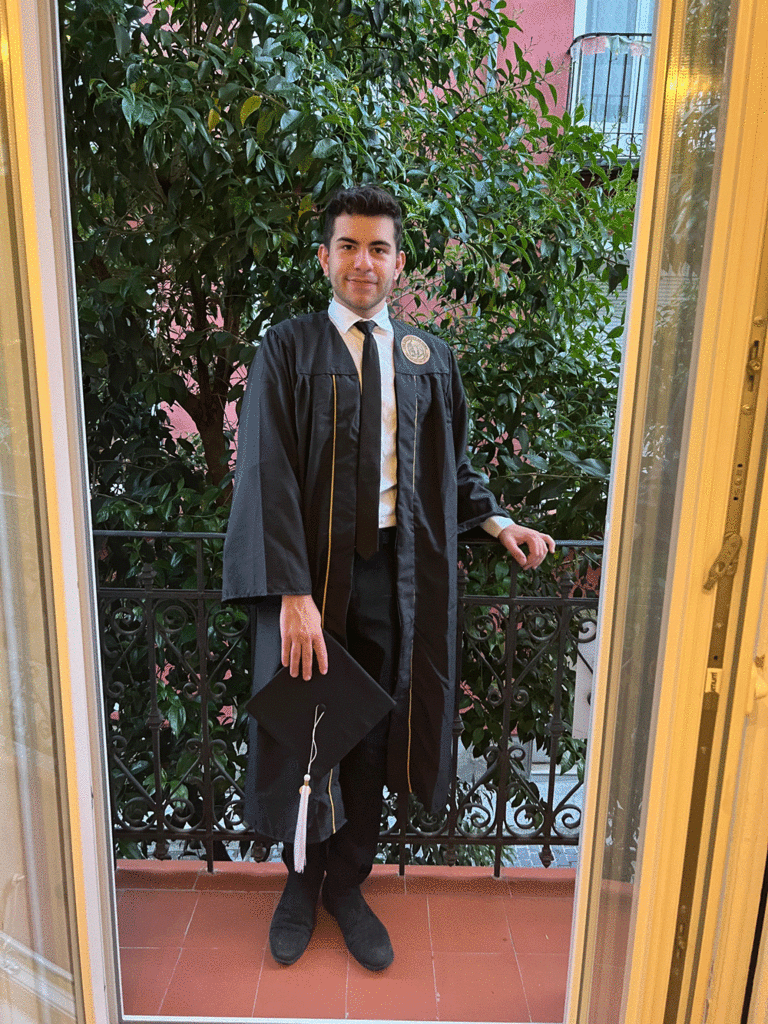 Kevin Drahos in graduation regalia on balcony