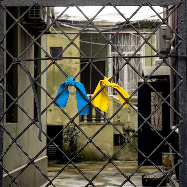 chainlink fence with blue and yellow ribbons 