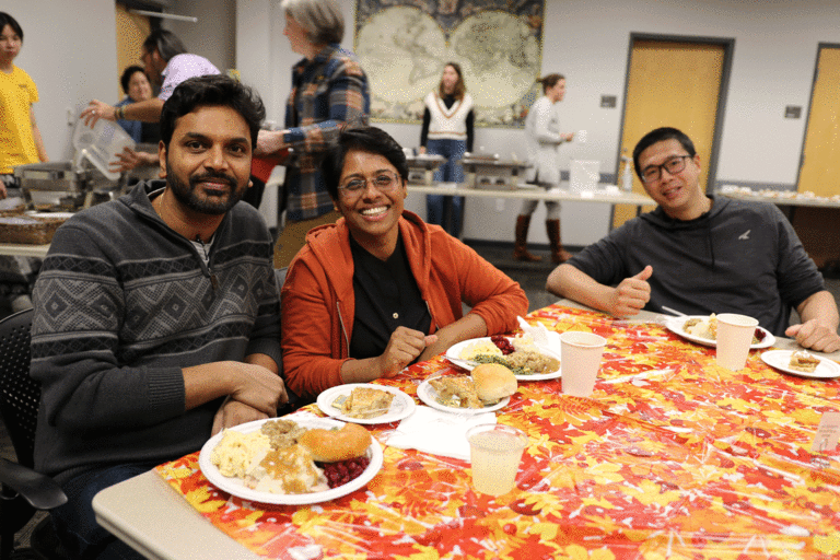 three people smiling at table