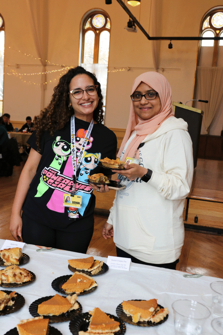 two students holding pie and smiling