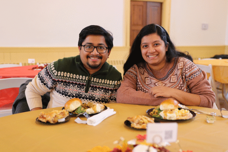 two students sitting at table smiling