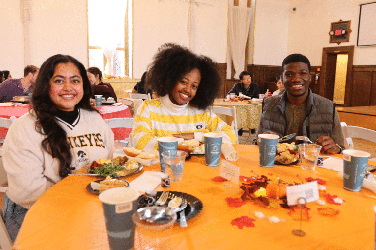 students with Thanksgiving meals at table smiling