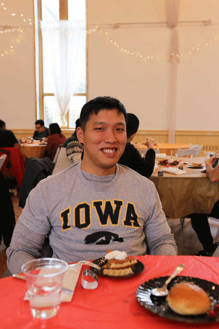 student with Iowa sweatshirt seated and smiling