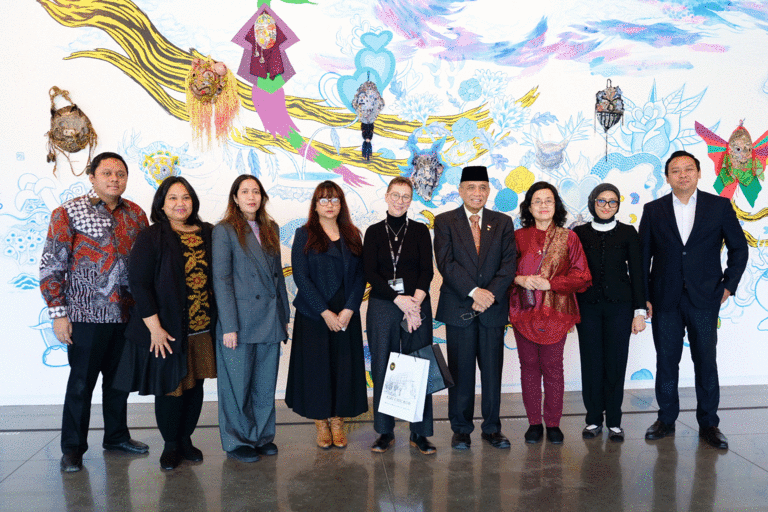 Indonesian delegation with Lauren Lessing standing in front of large mural at Stanley Museum of Art