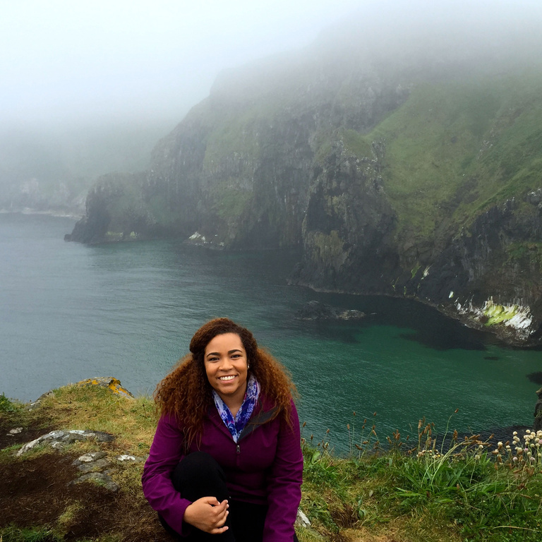 Rita Guzman in front of misty and foggy body of water and cliffs in Ireland