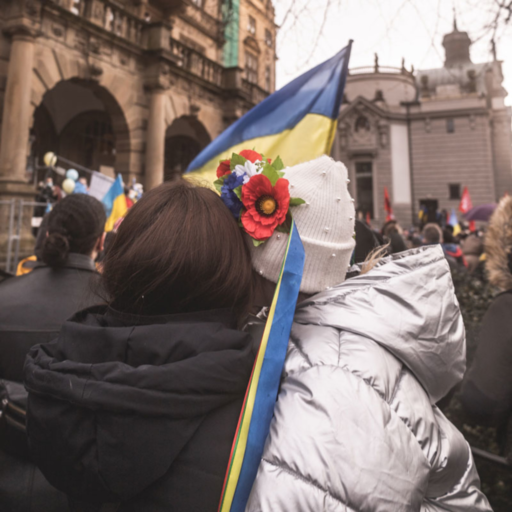 two people hug while holding a Ukrainian flag