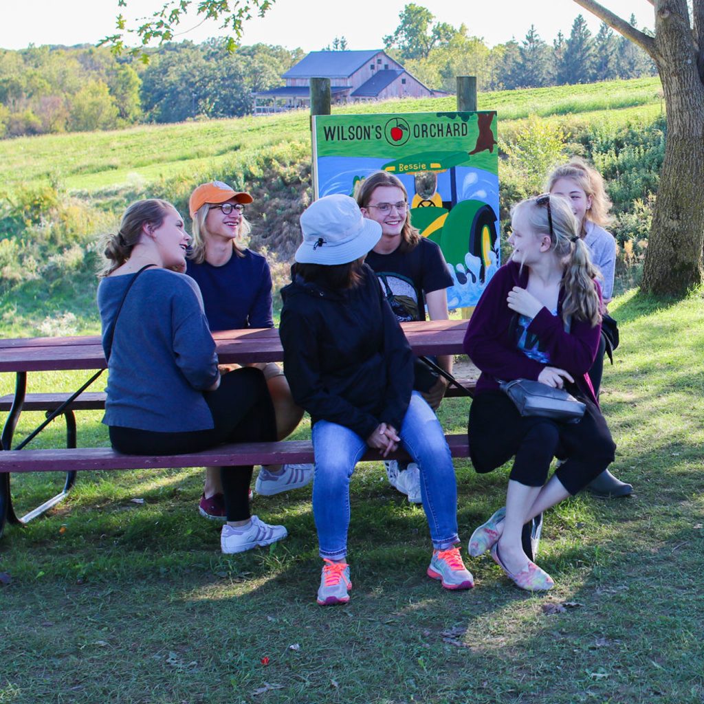 students sitting at picnic table at Wilson's Orchard smiling