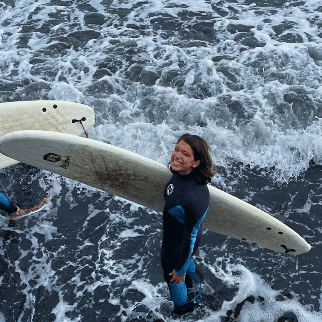 Bella Rivera holding surf board in water