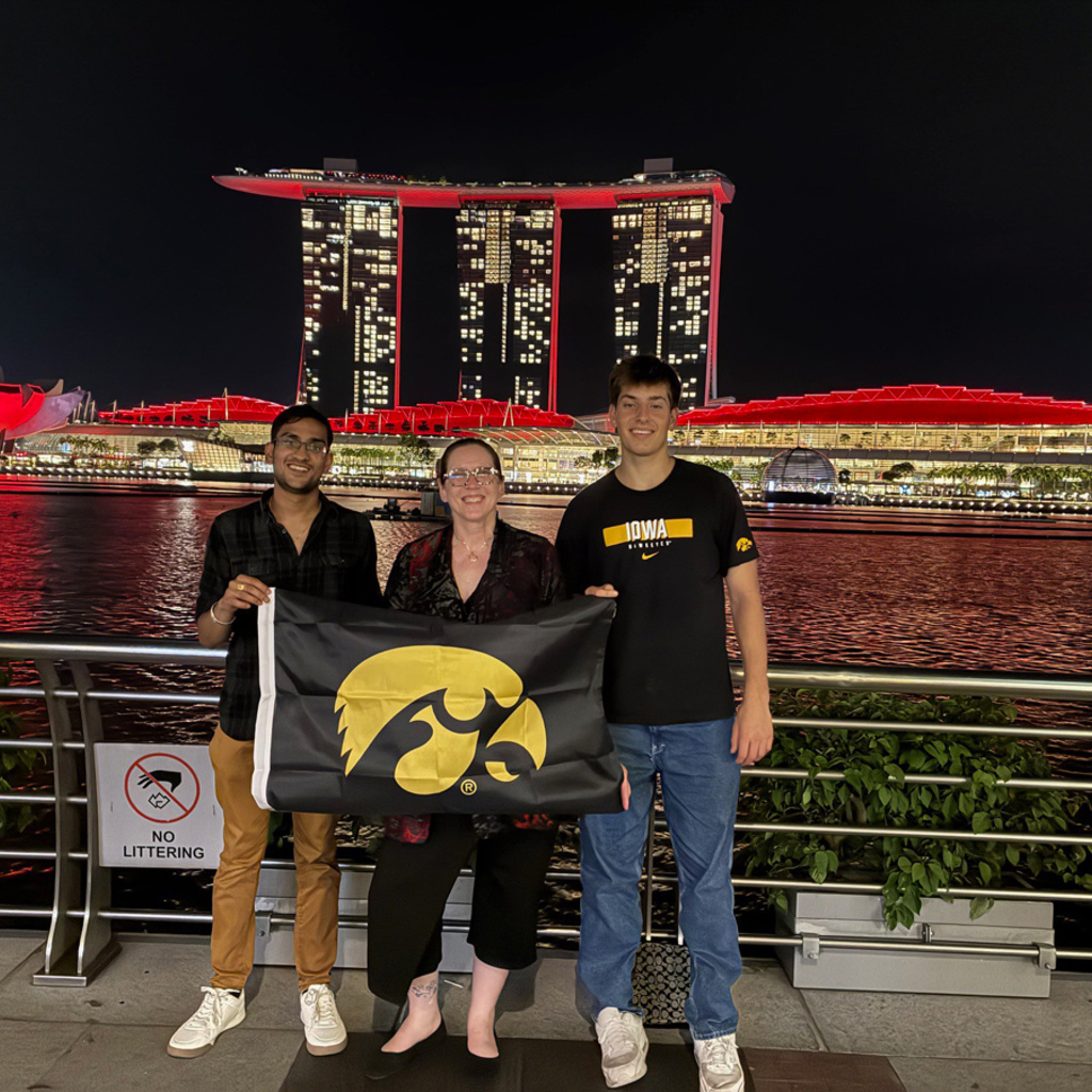 Monica Ernberger holding a Hawkeye flag with UI students in Singapore