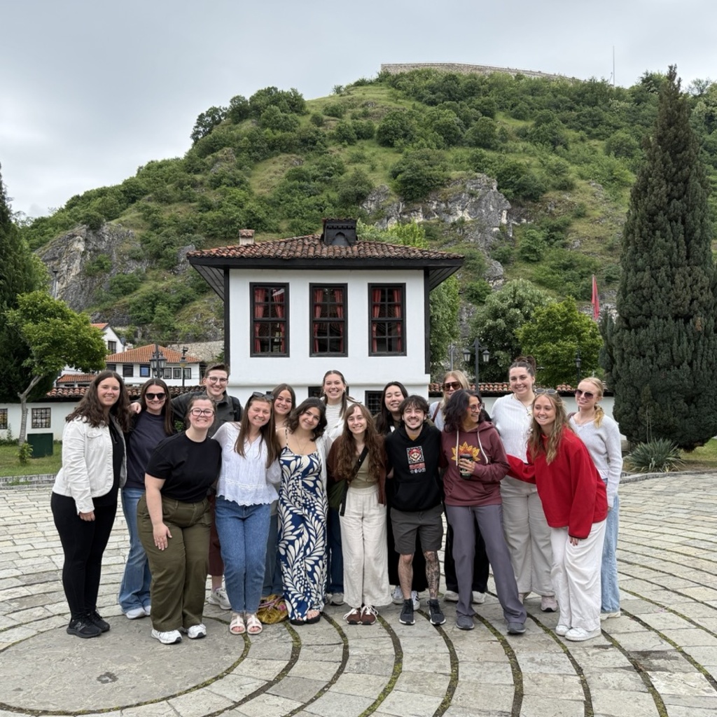 University of Iowa graduate students and professors, including Charlotte Hilker, pose in front of the Albanian League of Prizren.